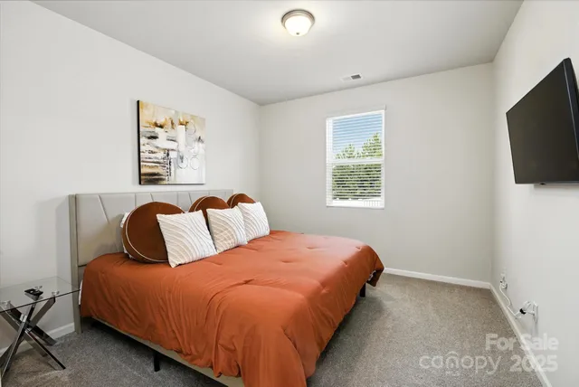 a bedroom with a bed and a flat tv screen on a dresser