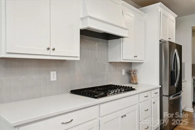 a kitchen with stainless steel appliances white cabinets and a stove a refrigerator a white countertops