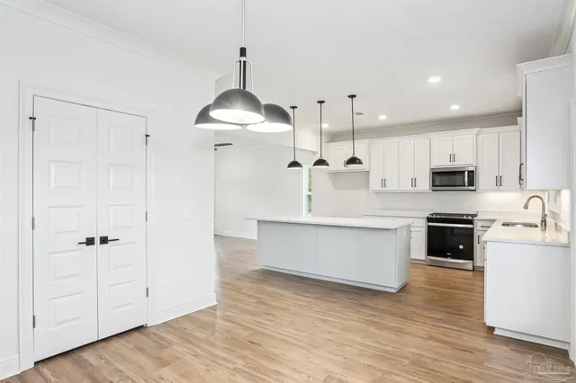 a large kitchen with cabinets wooden floor and stainless steel appliances