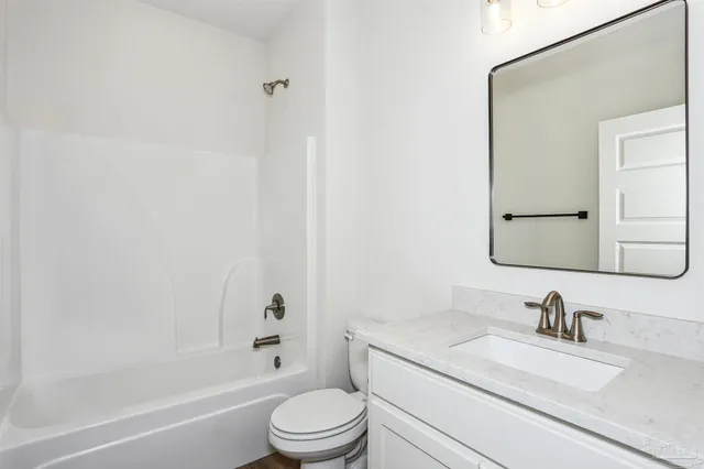 a bathroom with a granite countertop toilet a sink and a mirror