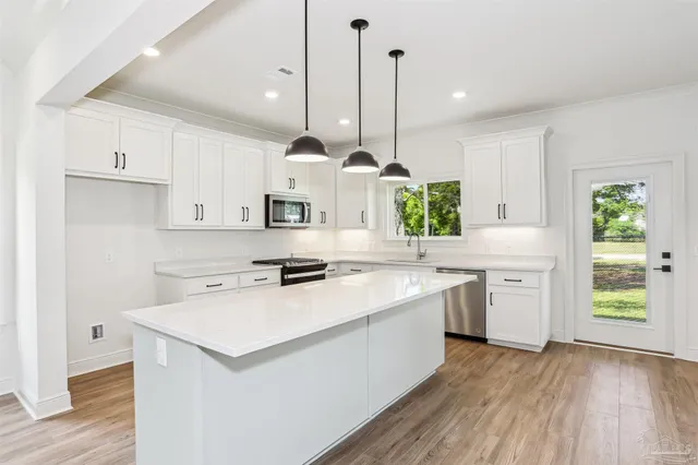 a kitchen with a stove a sink a center island and wooden floor