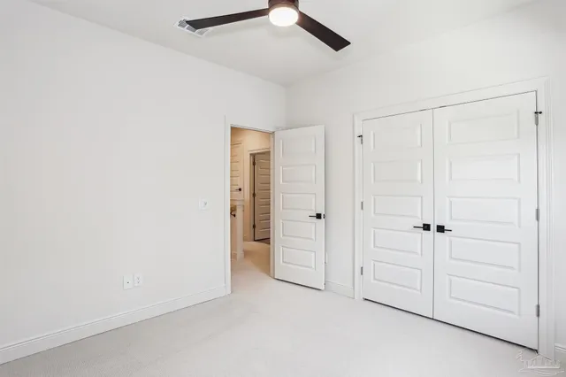 an empty room with closet and fan