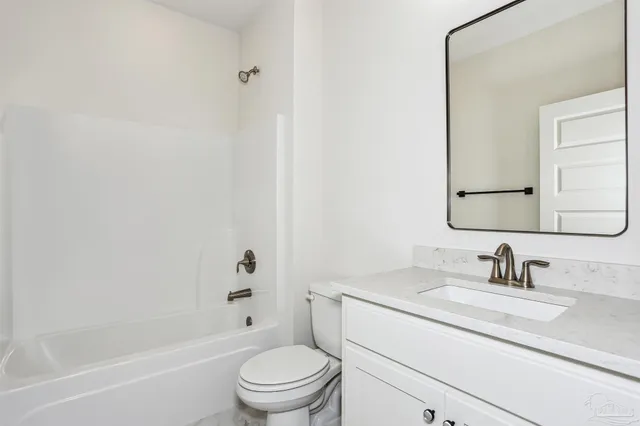 a bathroom with a toilet a sink a mirror a bathtub and vanity