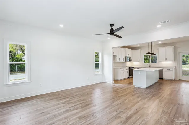 a large white kitchen with a white countertops a sink and a stove with wooden floor