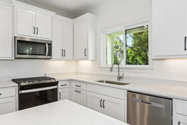 a kitchen with cabinets appliances a sink and a window