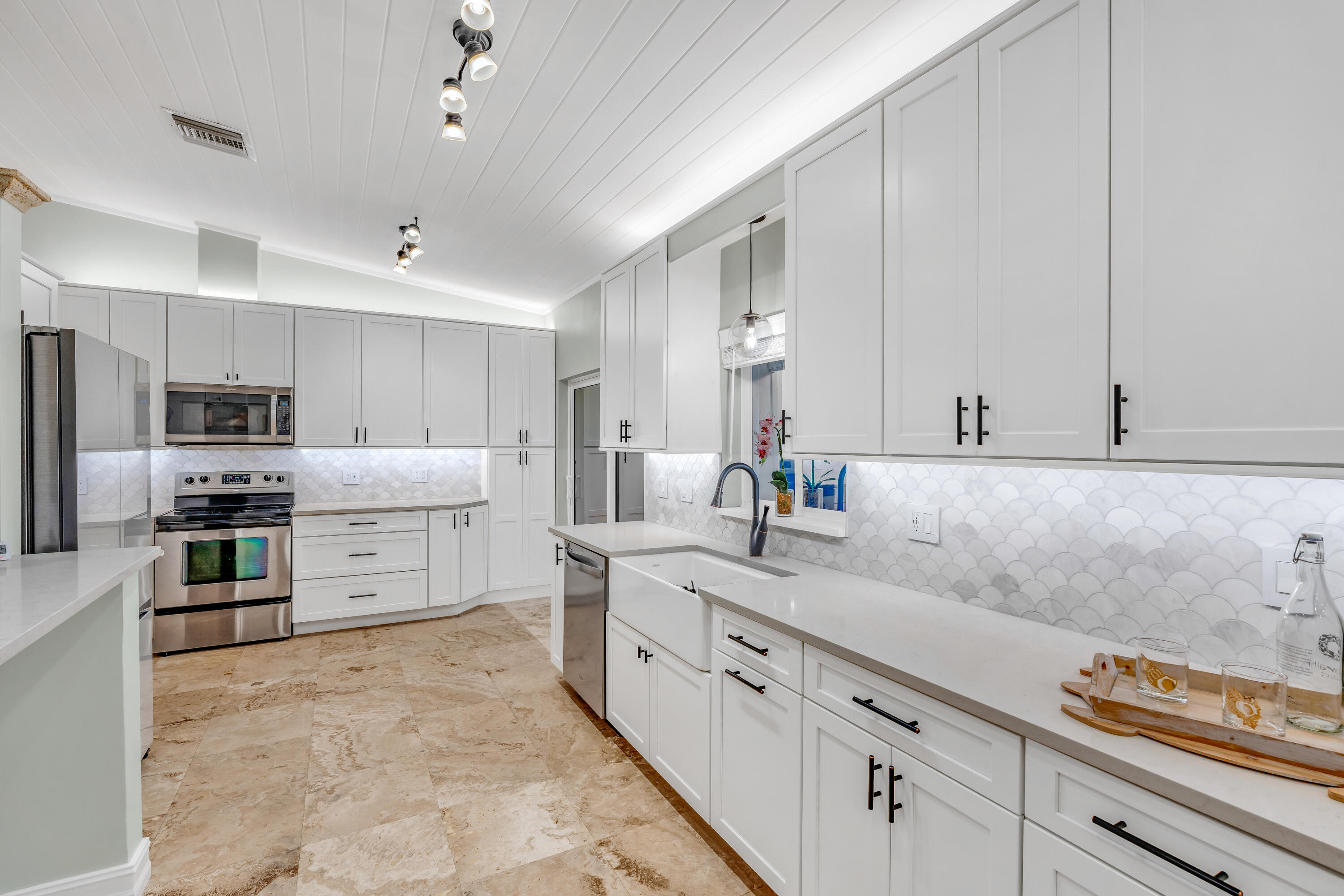 33 Blue Runner Street Key Largo, FL 33037 - Photo 18 of 60 a large white kitchen with stainless steel appliances granite countertop a stove oven a sink dishwasher and white cabinets next to a window