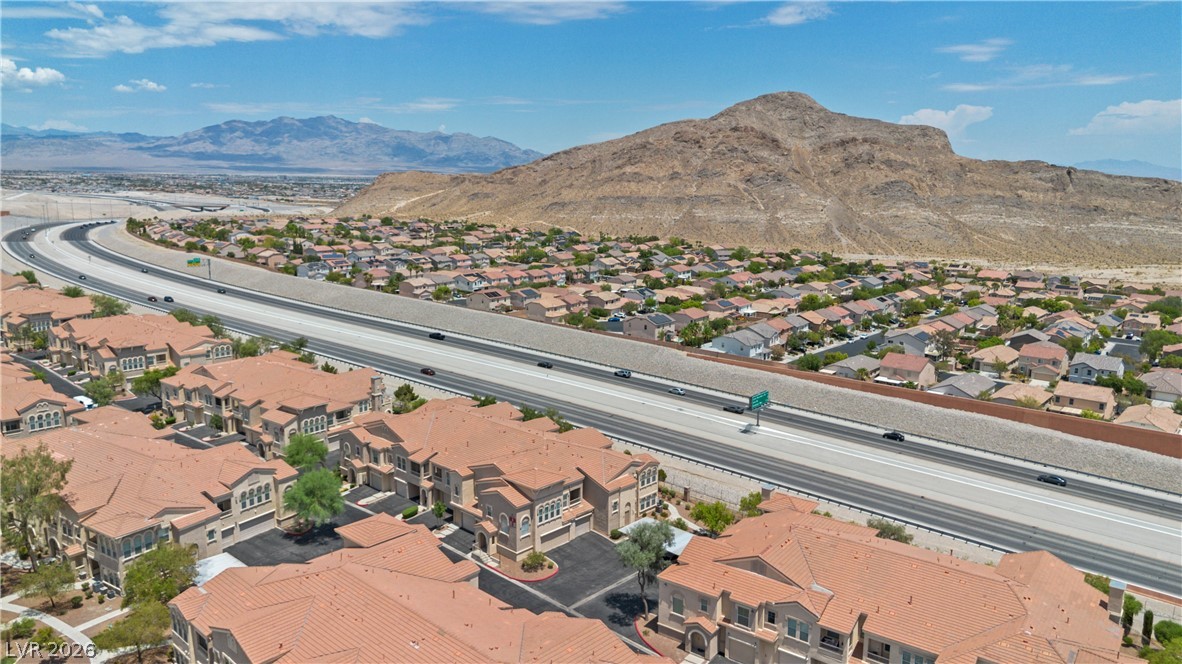 10550 West Alexander Road, Unit 1025 Las Vegas, NV 89129 - Photo 40 of 42 An aerial perspective reveals a residential community nestled beside a highway, with desert mountains providing a dramatic backdrop.