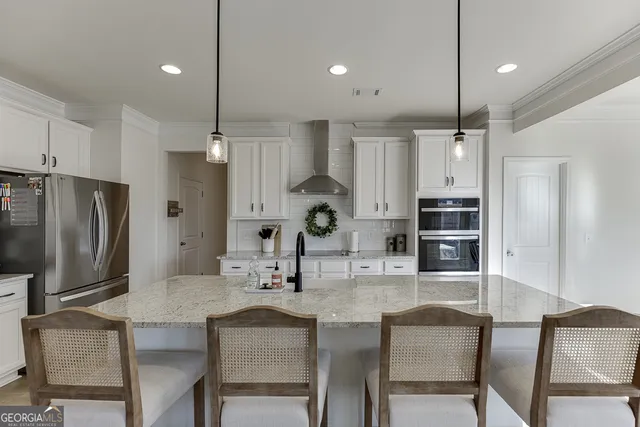 a kitchen with stainless steel appliances granite countertop a stove refrigerator a oven a sink a dining table and chairs with wooden floor