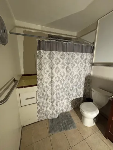 a bathroom with a toilet and a shower curtain