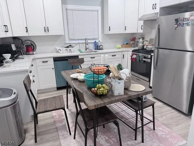 a kitchen with stainless steel appliances a dining table chairs and a refrigerator