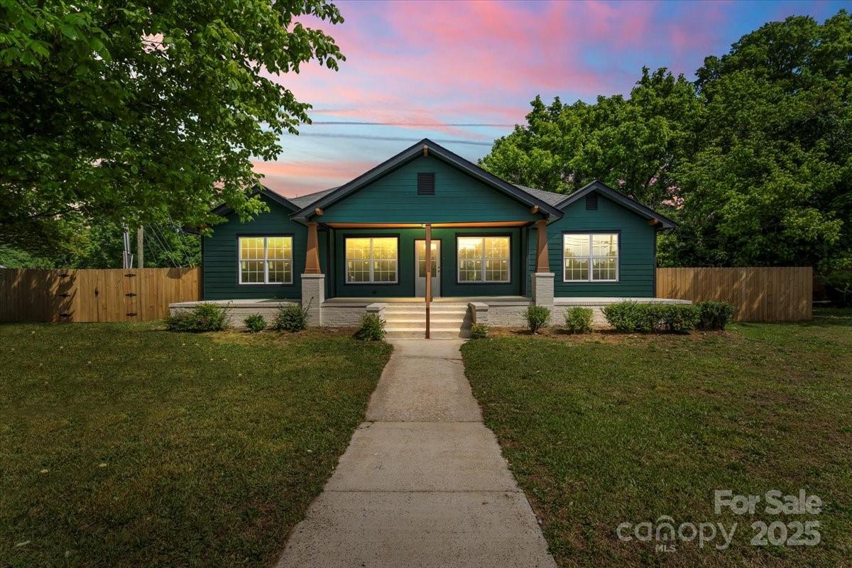 a view of a brick house with a big yard and large trees