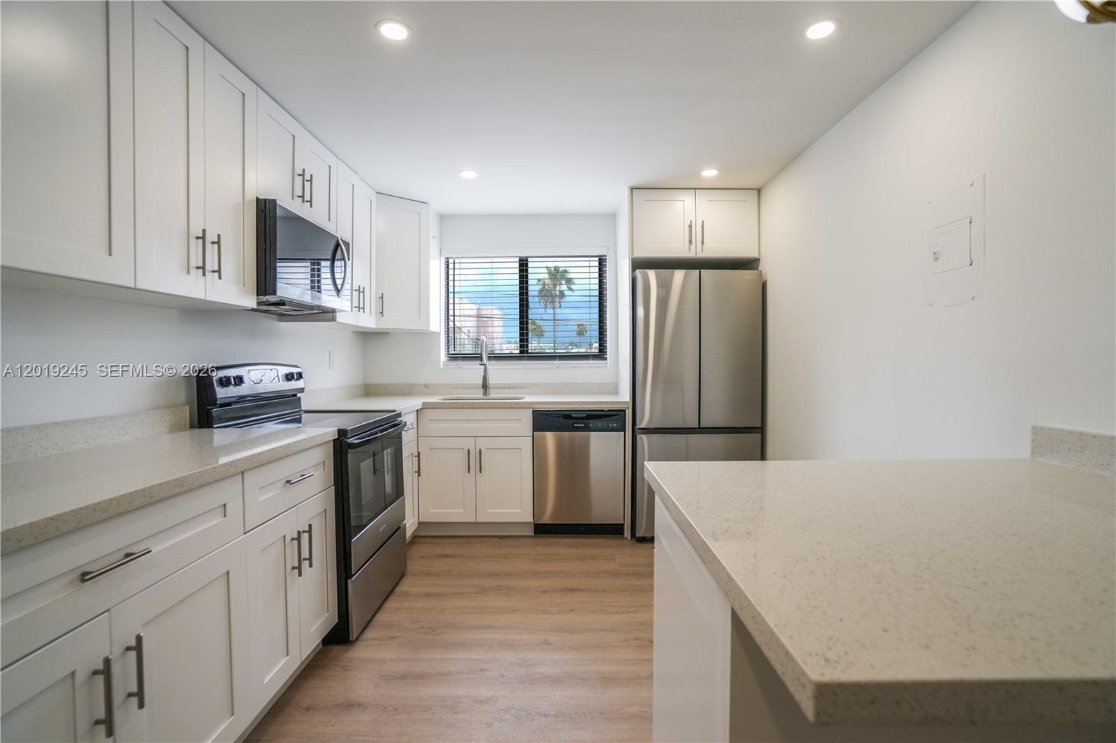 6960 Rue Vendome, Unit 201 Miami Beach, FL 33141 - Photo 7 of 27 a kitchen with a sink a stove a refrigerator and white cabinets