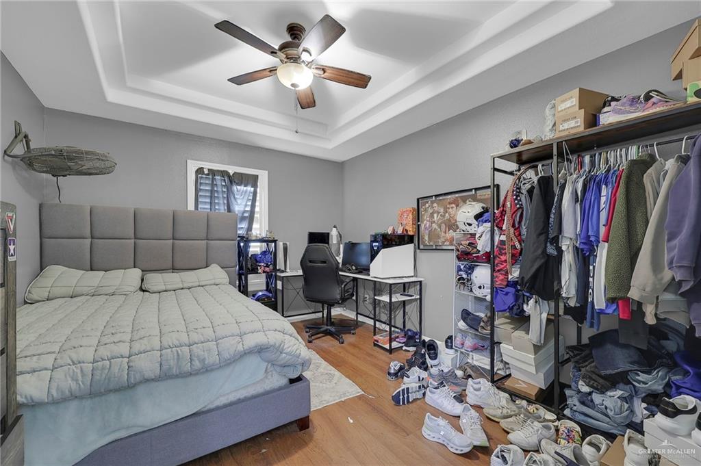 12813 North 106th Street Mission, TX 78573 - Photo 13 of 17 Bedroom featuring light wood-type flooring, a tray ceiling, a desk, and a ceiling fan