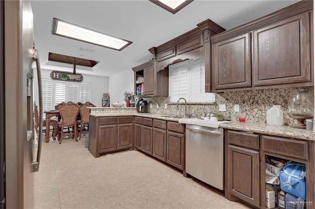 12813 North 106th Street Mission, TX 78573 - Photo 6 of 17 Kitchen featuring a raised ceiling, stainless steel appliances, dark brown cabinetry, decorative backsplash, and open shelves