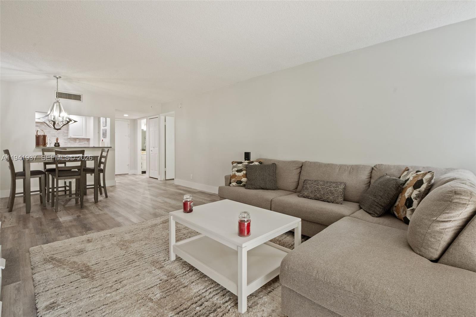 301 Racquet Club Road, Unit 104 Weston, FL 33326 - Photo 3 of 21 a living room with furniture and a dining table with kitchen view
