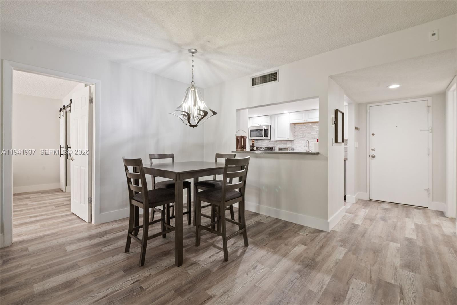 301 Racquet Club Road, Unit 104 Weston, FL 33326 - Photo 4 of 21 a view of a dining room and livingroom with furniture wooden floor a chandelier