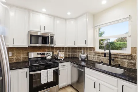 a kitchen with stainless steel appliances granite countertop a sink a stove and a microwave
