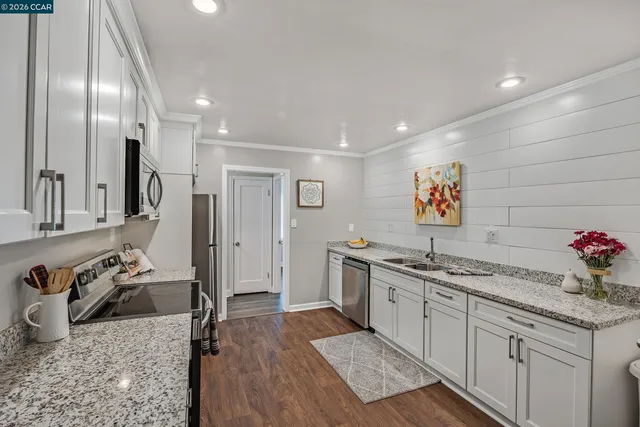 a kitchen with granite countertop a sink stainless steel appliances and cabinets