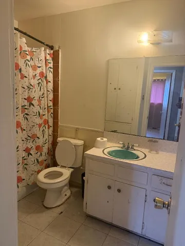 a bathroom with a granite countertop toilet a sink and a mirror