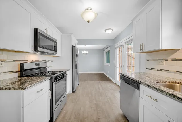 a kitchen with granite countertop stainless steel appliances a stove cabinets and wooden floor