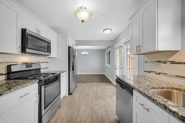 a kitchen with stainless steel appliances granite countertop a stove a sink and a microwave