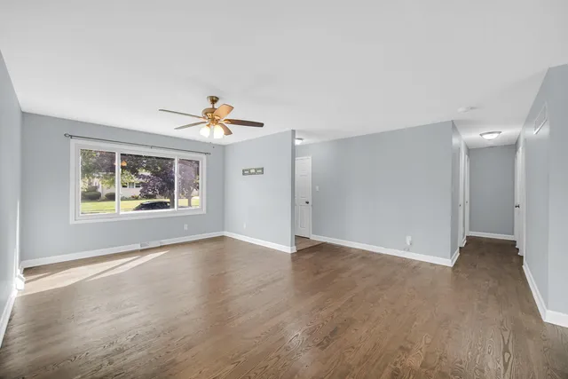 a view of an empty room with a window and wooden floor