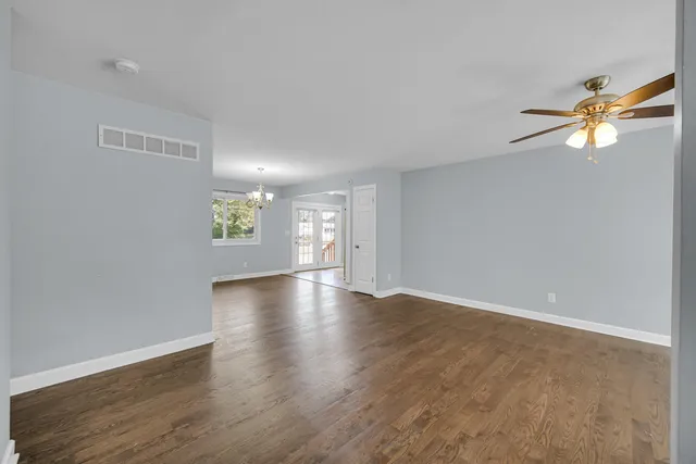 a view of an empty room with window and wooden floor