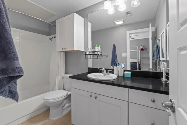 a bathroom with a granite countertop sink a toilet a mirror and shower