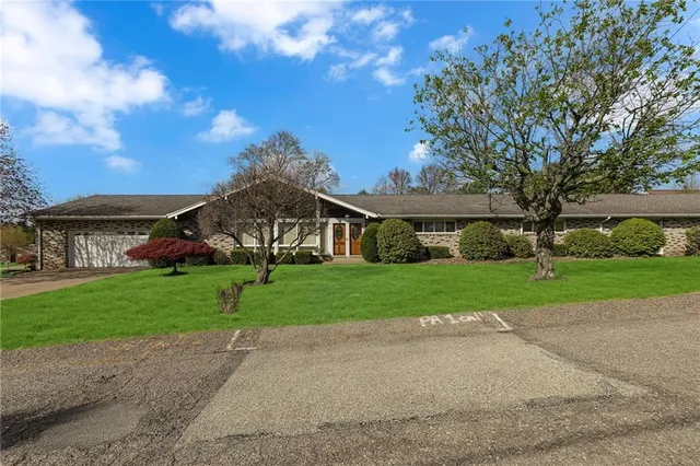 a view of a big house with a big yard and large trees