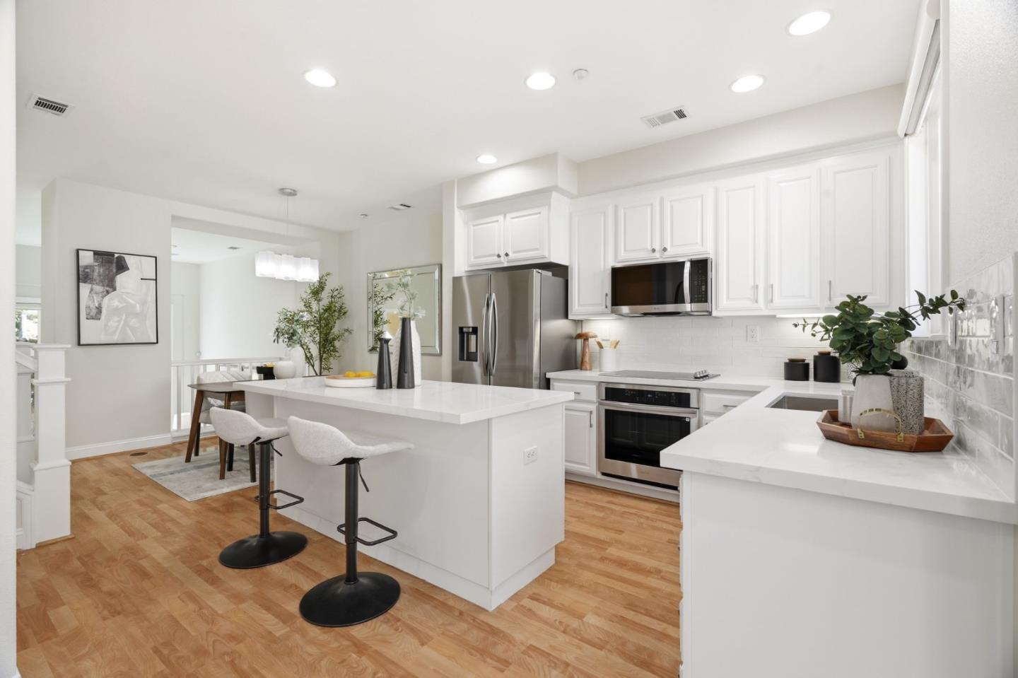 5050 Ruffino Terrace San Jose, CA 95129 - Photo 4 of 26 a kitchen with stainless steel appliances kitchen island granite countertop a stove a sink a refrigerator and a dining table with wooden floor