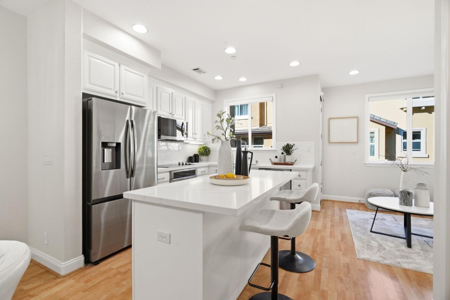 5050 Ruffino Terrace San Jose, CA 95129 - Photo 9 of 26 a kitchen with stainless steel appliances kitchen island granite countertop a refrigerator a stove a sink dishwasher and white cabinets with wooden floor