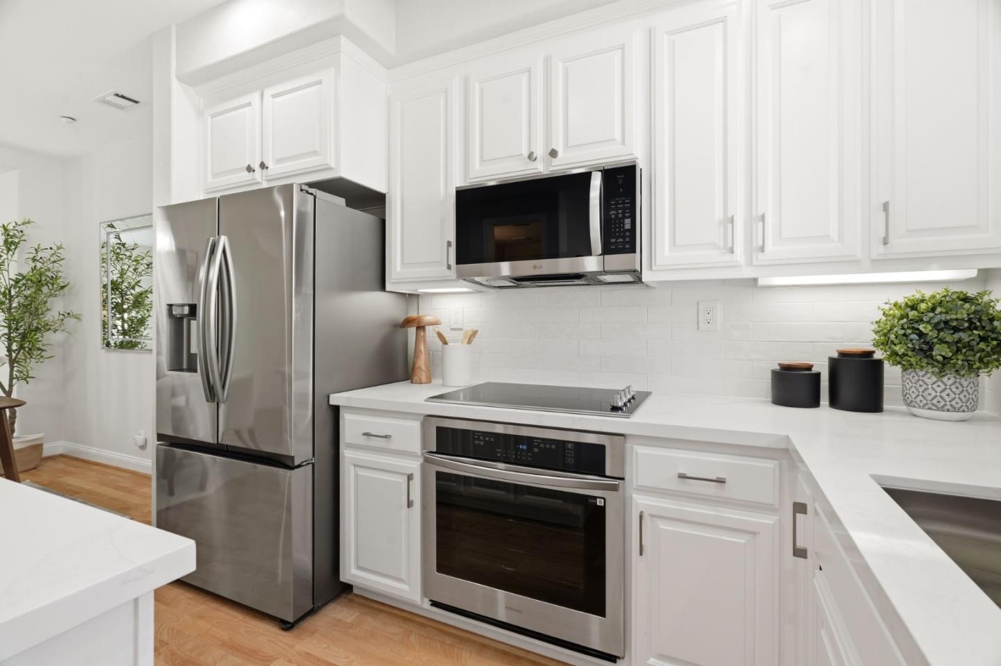 5050 Ruffino Terrace San Jose, CA 95129 - Photo 10 of 26 a kitchen with white cabinets and stainless steel appliances