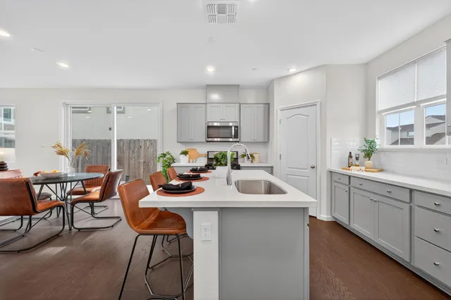 a kitchen with a sink white cabinets and chairs