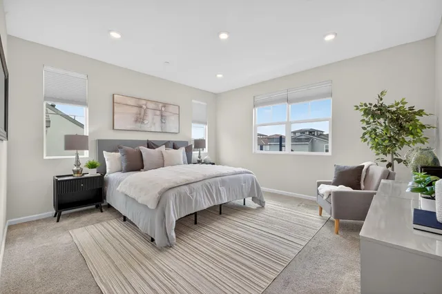 a bedroom with a large bed a couch and potted plant