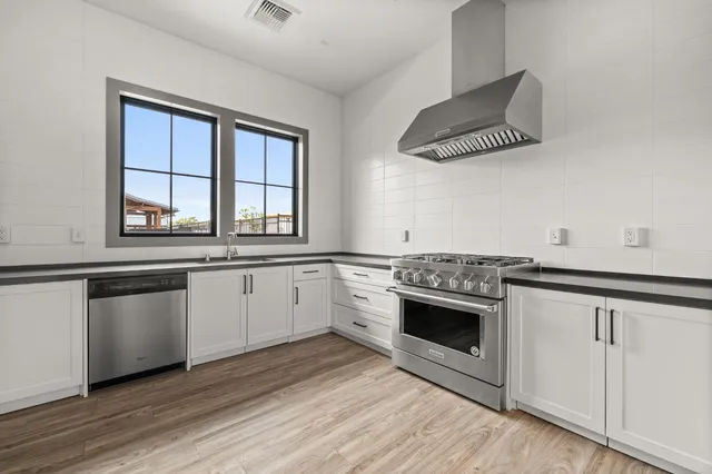 a kitchen with stainless steel appliances white cabinets a sink and a stove