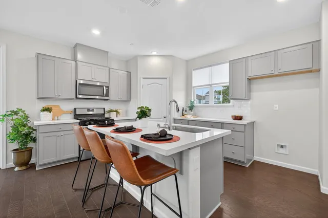 a kitchen with a stove a sink a kitchen island with a dining table and chairs