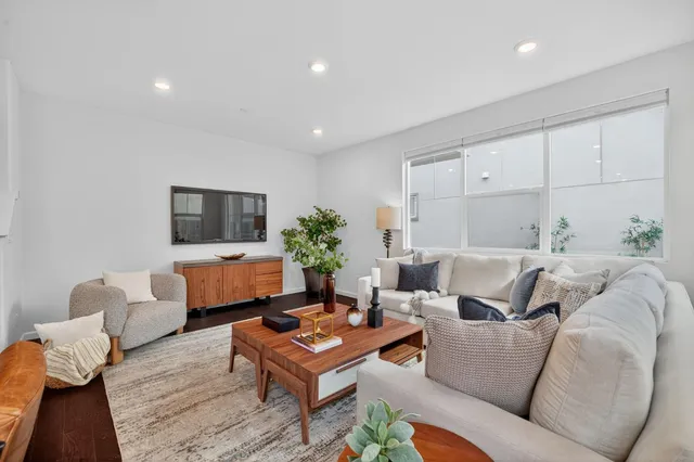 a living room with furniture a flat screen tv and a potted plant
