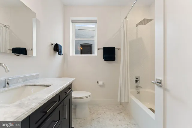 a bathroom with a granite countertop sink a toilet and shower