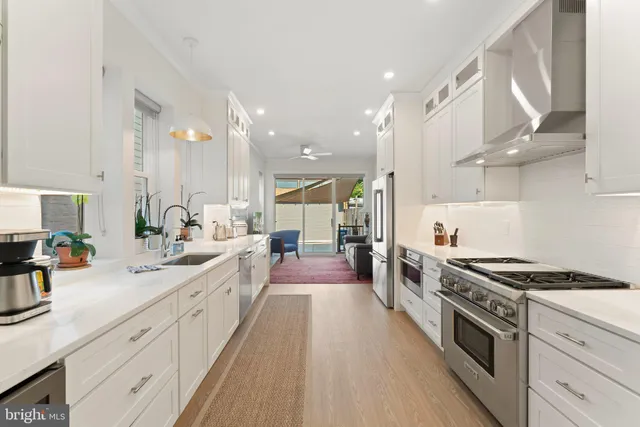 a large kitchen with stainless steel appliances a sink a counter top space and cabinets