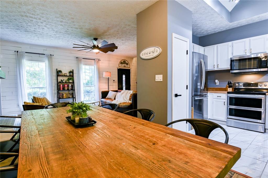 40 Mildred Lane Covington, GA 30016 - Photo 26 of 56 a large kitchen with stainless steel appliances a stove a refrigerator a sink a dining table and chairs with wooden floor