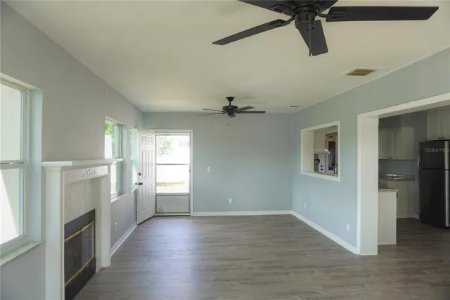 a view of an empty room with a window and a kitchen