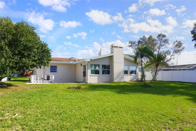 a view of a house with a yard and a large tree