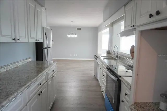 a kitchen with granite countertop a sink stove and cabinets