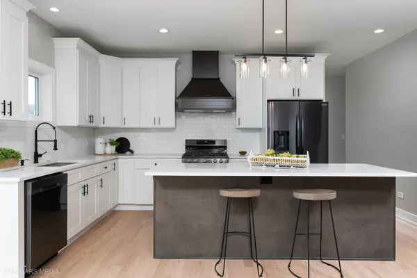 a kitchen with stainless steel appliances granite countertop a sink a stove a refrigerator and island with wooden floor