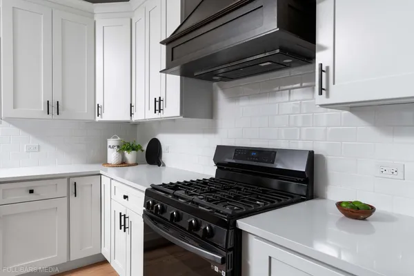 a kitchen with a stove and white cabinets