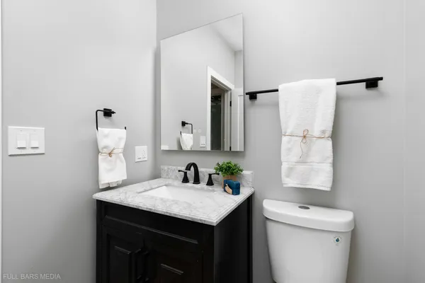 a bathroom with a sink vanity toilet and a mirror