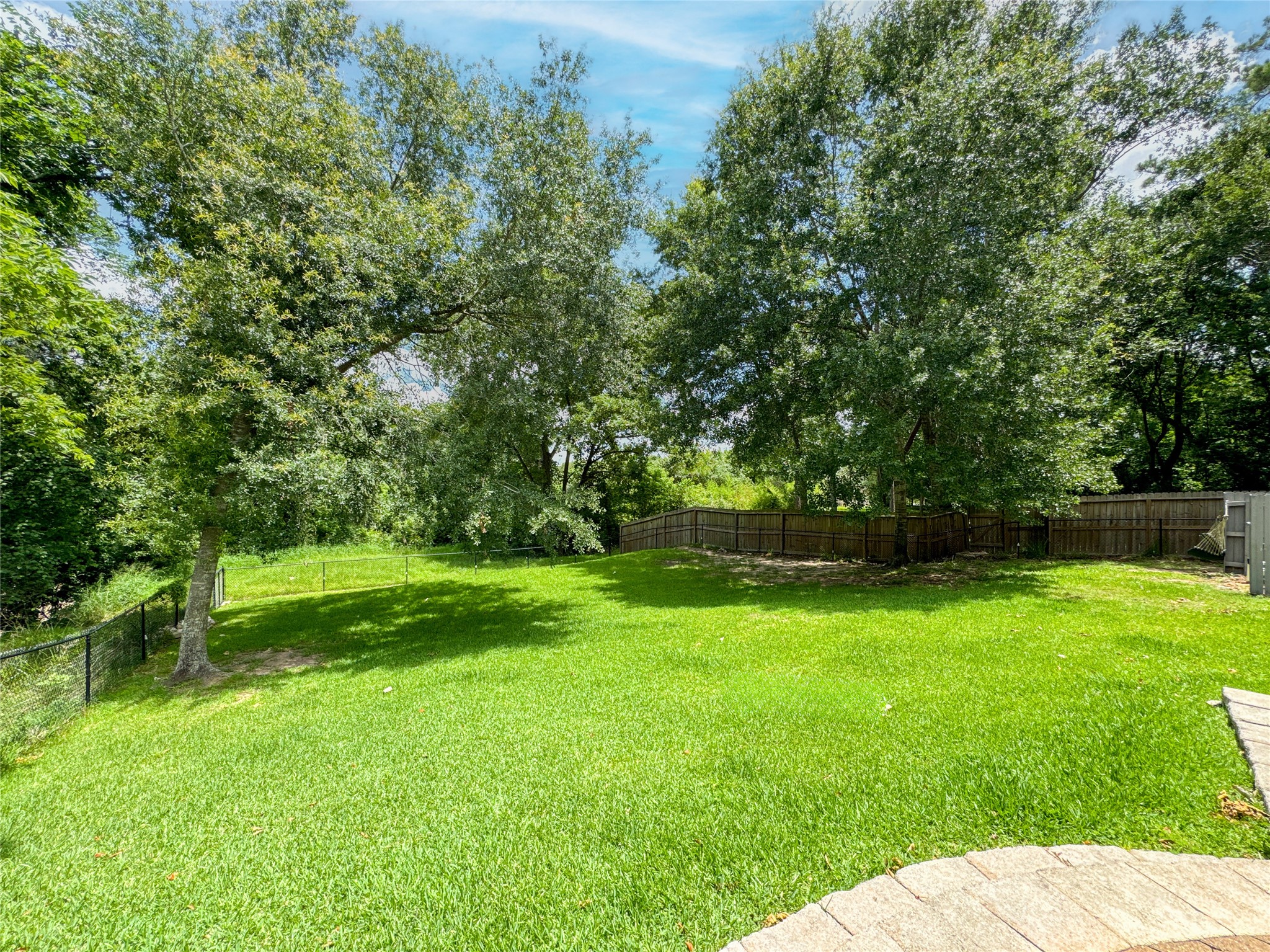 1810 Woerner Road Houston, TX 77090 - Photo 37 of 39 Expansive backyard with lush greenery, mature trees, and a private fence—perfect for relaxation and outdoor activities.