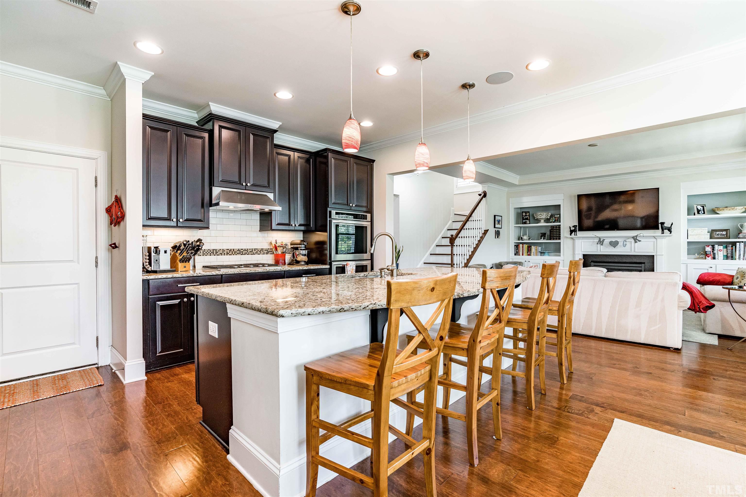 4020 Periwinkle Blue Lane Raleigh, NC 27612 - Photo 8 of 40 a kitchen with stainless steel appliances kitchen island granite countertop a refrigerator a stove and a wooden floor