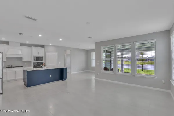 a large hall with a large window and kitchen view