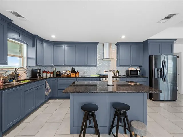 a kitchen with granite countertop a table chairs microwave and refrigerator